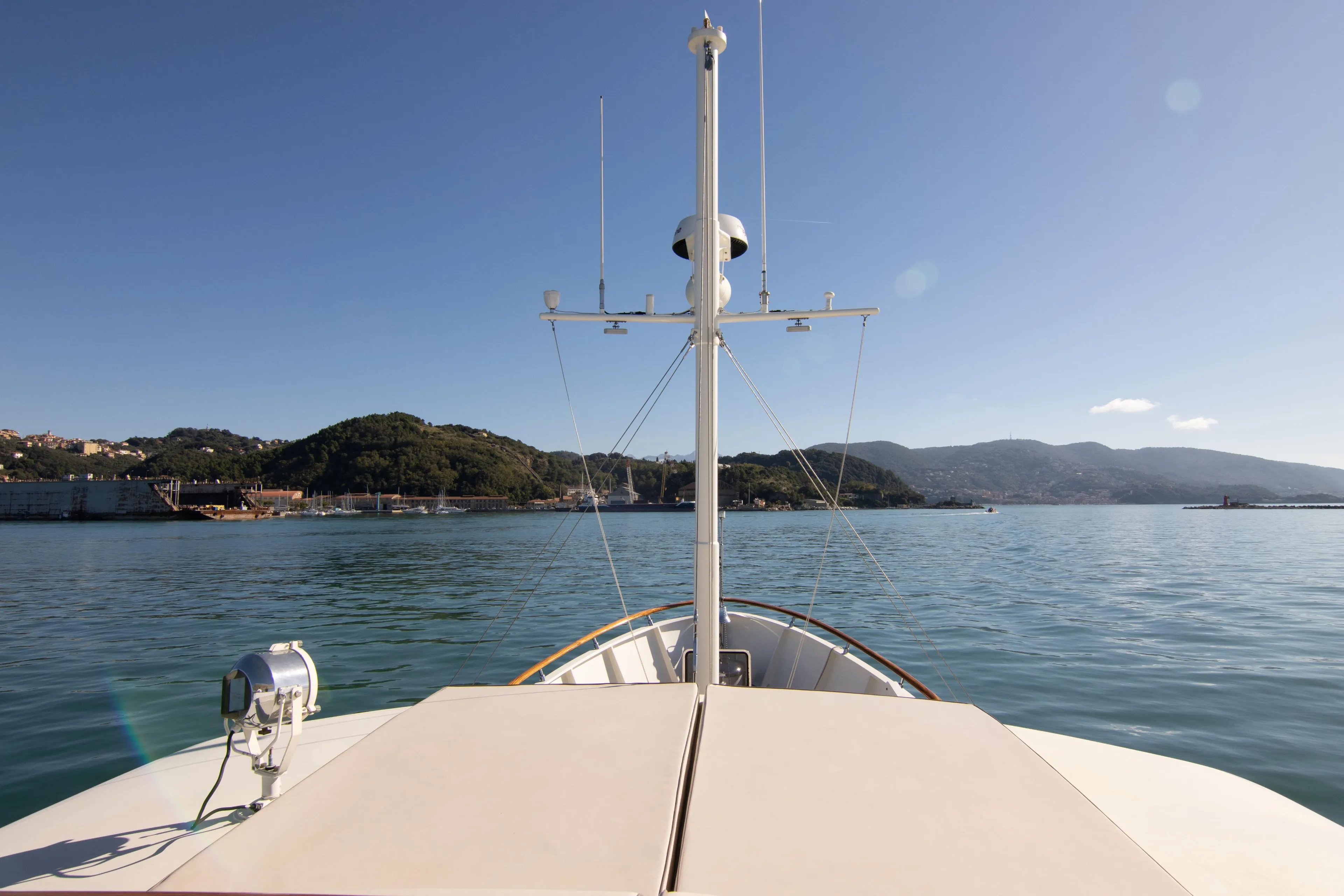 Bow view of 2000 Bugari NAVETTA yacht on calm waters with scenic hills.