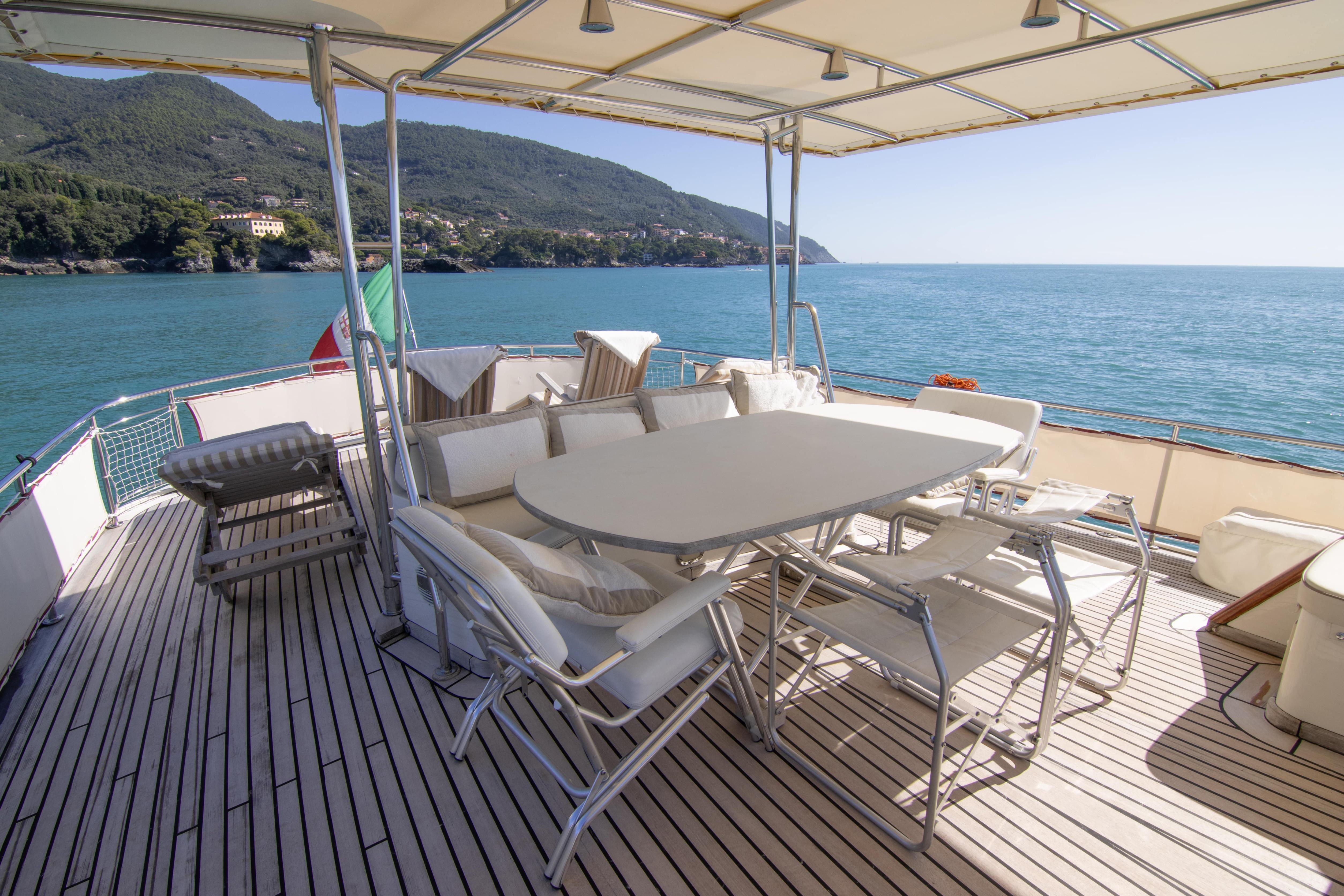 Luxurious Bugari NAVETTA 2000 yacht deck with seating, overlooking serene ocean and coastal landscape.