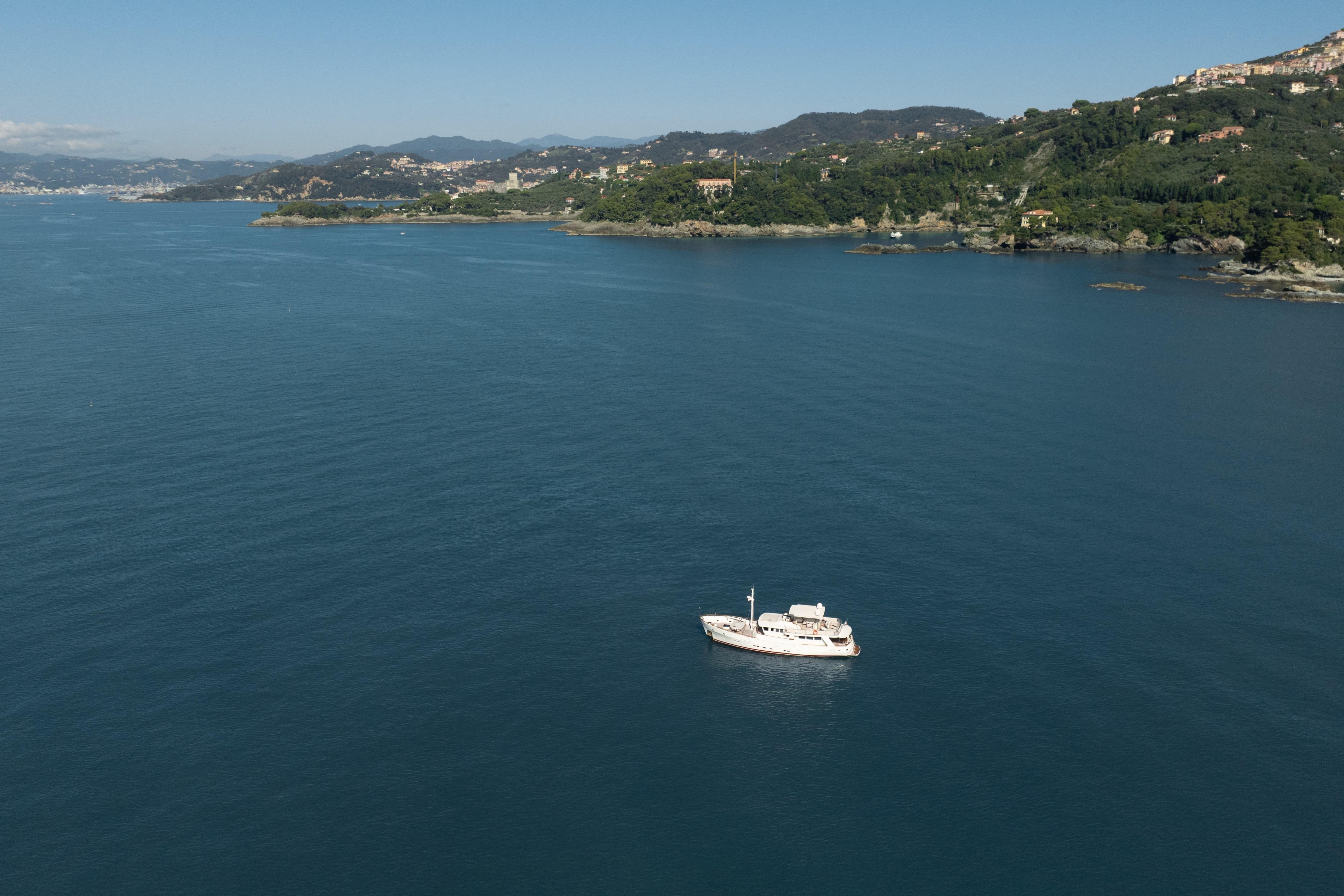 Bugari NAVETTA 2000 yacht cruising on serene coastal waters with lush green hills.