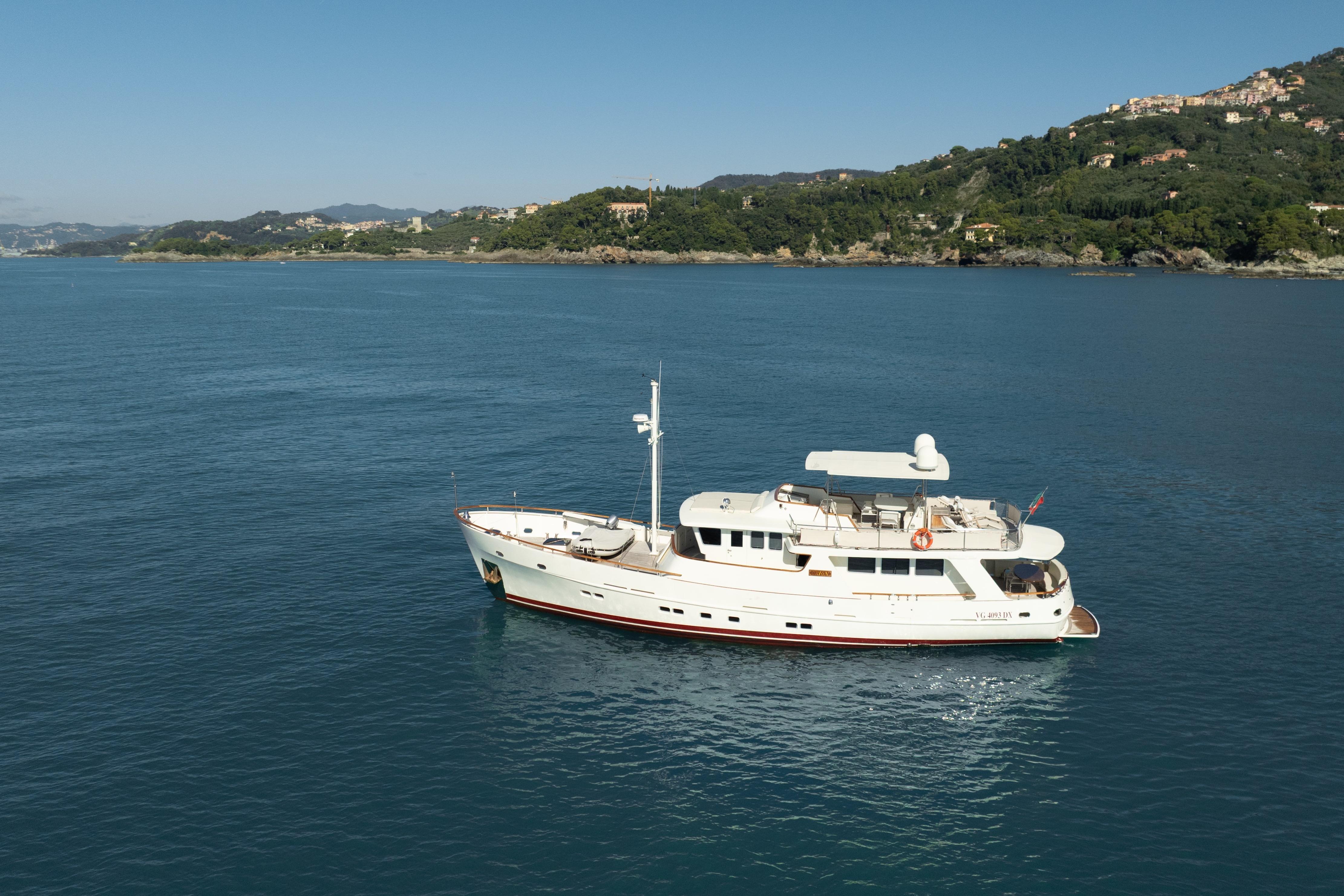 Luxury Bugari NAVETTA yacht from 2000 cruising near scenic coastline.