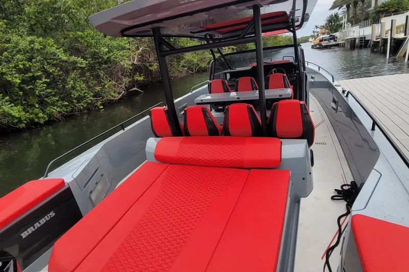  Yacht Photos Pics 2022 Axopar Brabus Shadow 900 ST with vibrant red seating, docked by lush greenery.