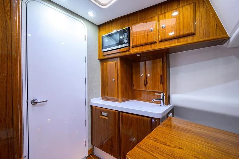  Yacht Photos Pics Luxurious 2021 HCB 53 Sueños yacht interior with wood cabinetry and modern kitchenette.