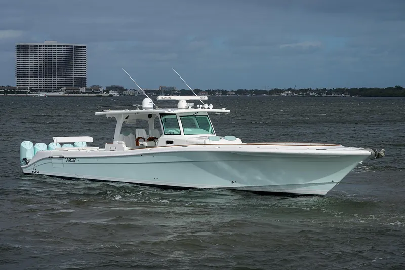  Yacht Photos Pics 2021 HCB 53 Sueños boat cruising on a calm sea with a cityscape backdrop.
