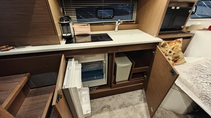  Yacht Photos Pics Interior of 2021 Jeanneau CAP CAMARAT 12.5WA boat kitchen with open cabinets.