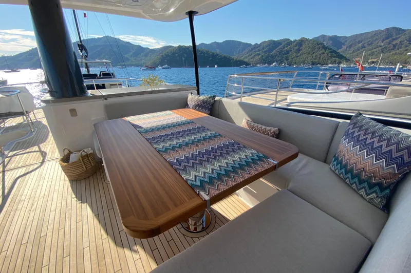  Yacht Photos Pics Luxurious Azimut Magellano 66 yacht deck with elegant seating, wooden table, and scenic ocean view.