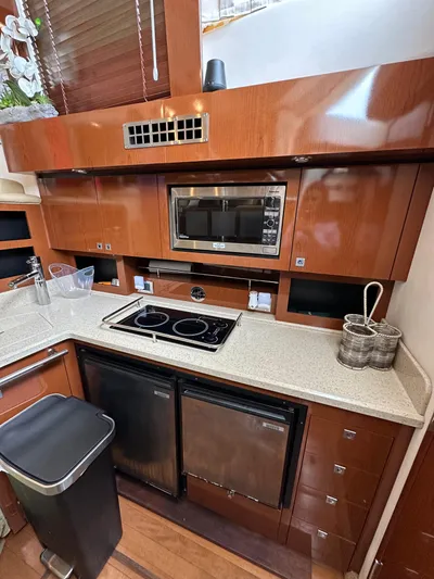  Yacht Photos Pics 2009 Sea Ray 36 Sedan Bridge kitchen with microwave, stove, and wooden cabinetry.