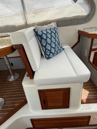 Outcast Yacht Photos Pics White cushioned seating with blue patterned pillow on 2004 Mabry 40 boat interior.