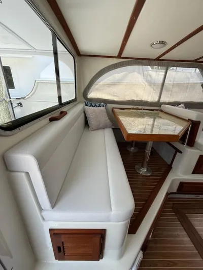 Outcast Yacht Photos Pics Interior of a 2004 Mabry 40 boat with cushioned seating and a wooden table.