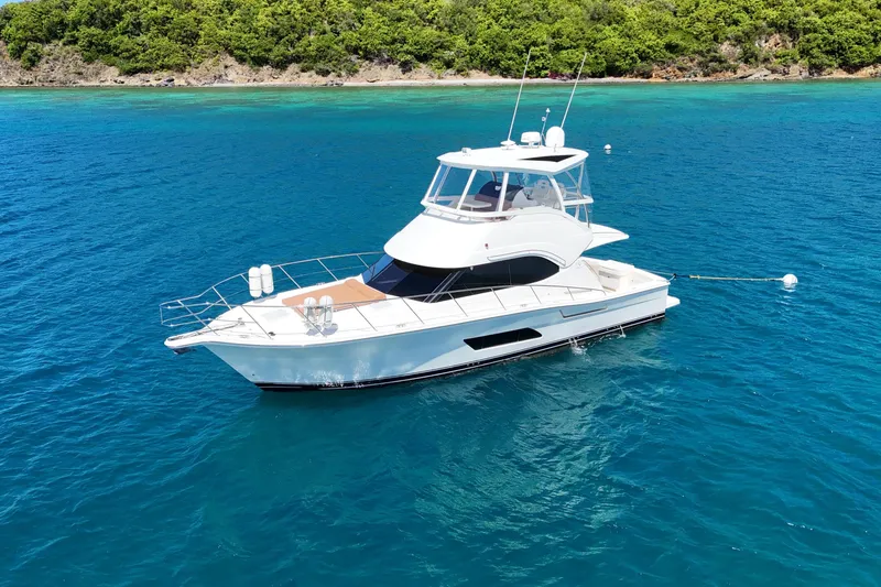  Yacht Photos Pics 2012 Riviera 43 Flybridge yacht on clear blue water near lush green shoreline.