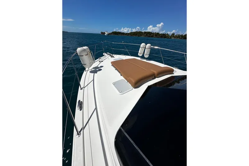  Yacht Photos Pics 2012 Riviera 43 Flybridge yacht with sunbed on deck, cruising in clear blue waters.