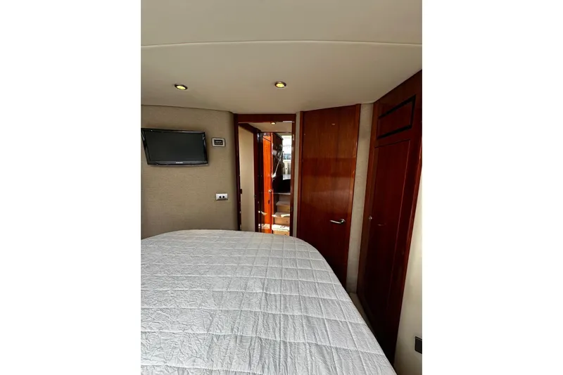  Yacht Photos Pics Interior of 2012 Riviera 43 Flybridge yacht bedroom with TV and wooden accents.