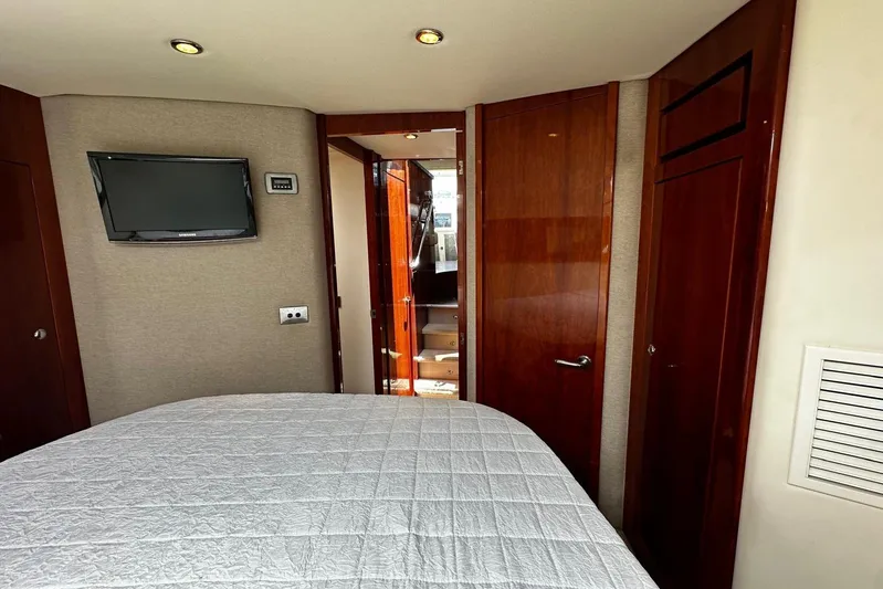  Yacht Photos Pics Bedroom interior of 2012 Riviera 43 Flybridge yacht with TV and wooden doors.