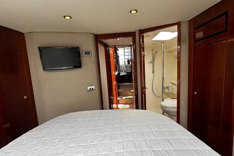 Yacht Photos Pics Bedroom and bathroom interior of 2012 Riviera 43 Flybridge yacht with TV and wood accents.