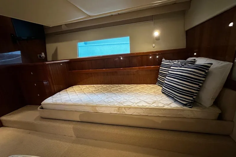  Yacht Photos Pics Luxurious cabin interior of 2012 Riviera 43 Flybridge yacht with bed and striped pillows.