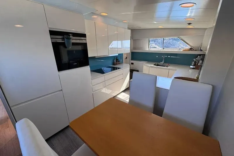  Yacht Photos Pics Modern kitchen interior on 2000 Sanlorenzo SL88 yacht, featuring sleek white cabinetry and dining area.