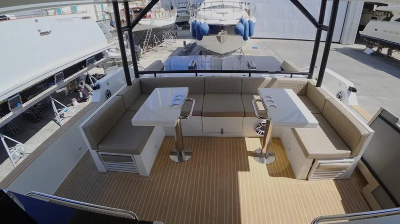  Yacht Photos Pics 2024 De Antonio Yachts D50 deck with seating and tables, docked in a marina.