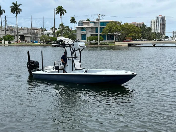  Yacht Photos Pics 2019 Yellowfin 24 Bay CE boat on water, urban backdrop, palm trees, overcast sky.