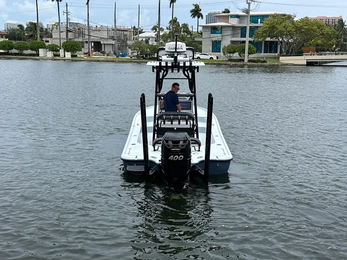  Yacht Photos Pics 2019 Yellowfin 24 Bay CE boat on water, with a person steering near waterfront buildings.