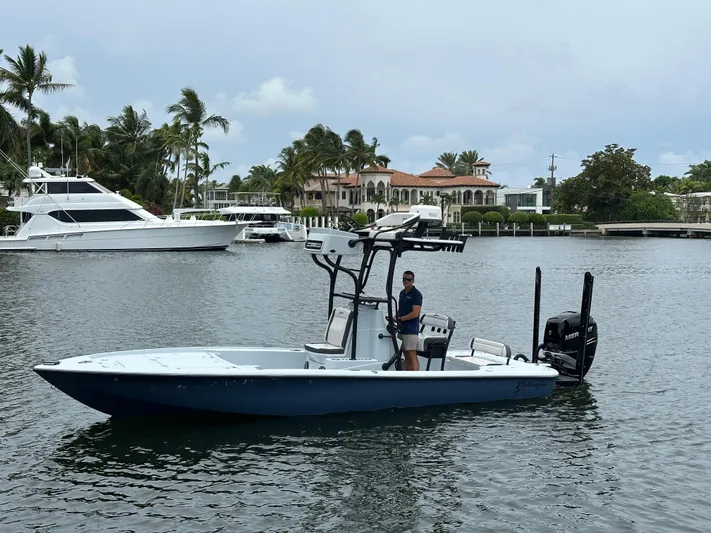  Yacht Photos Pics 2019 Yellowfin 24 Bay CE boat on water, with palm trees and luxury homes in background.