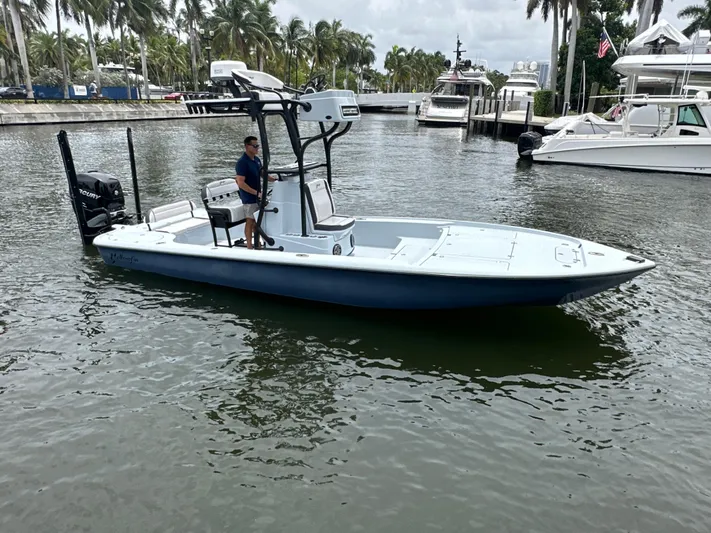  Yacht Photos Pics 2019 Yellowfin 24 Bay CE boat on water, surrounded by palm trees and yachts.