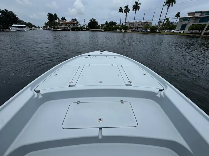 Yacht Photos Pics 2019 Yellowfin 24 Bay CE boat on calm waterway with palm trees in background.