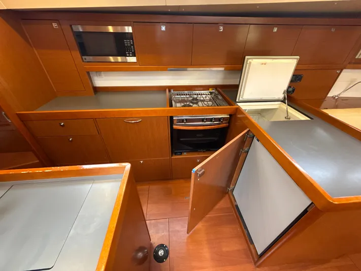 Samba Yacht Photos Pics Galley kitchen in 2012 Beneteau Oceanis 48 yacht with stove, microwave, and refrigerator.