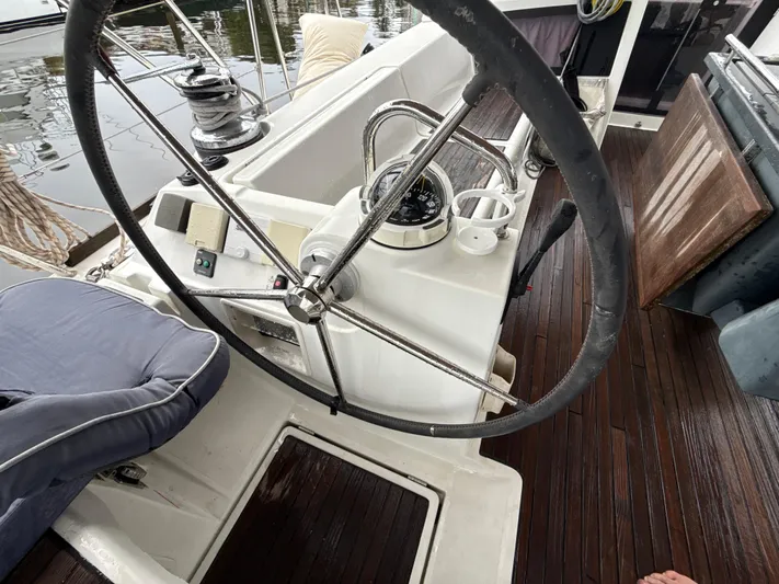 Samba Yacht Photos Pics Steering wheel of 2012 Beneteau Oceanis 48 sailboat with wooden deck and nautical equipment.