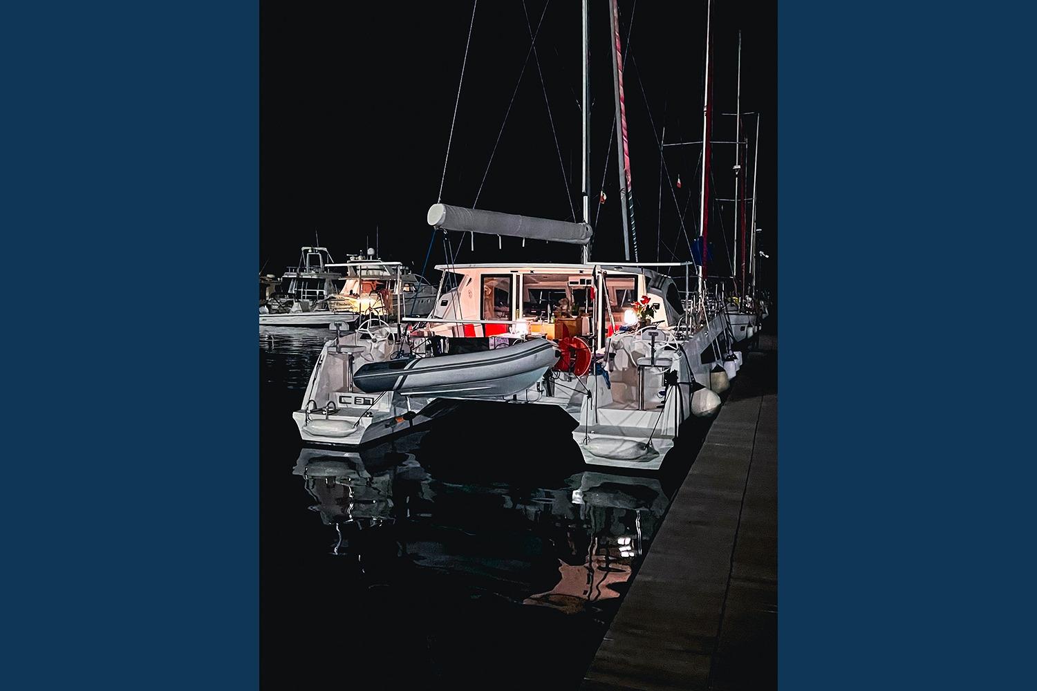 Night view of a 2021 Comar C-CAT 37 catamaran docked at a marina.