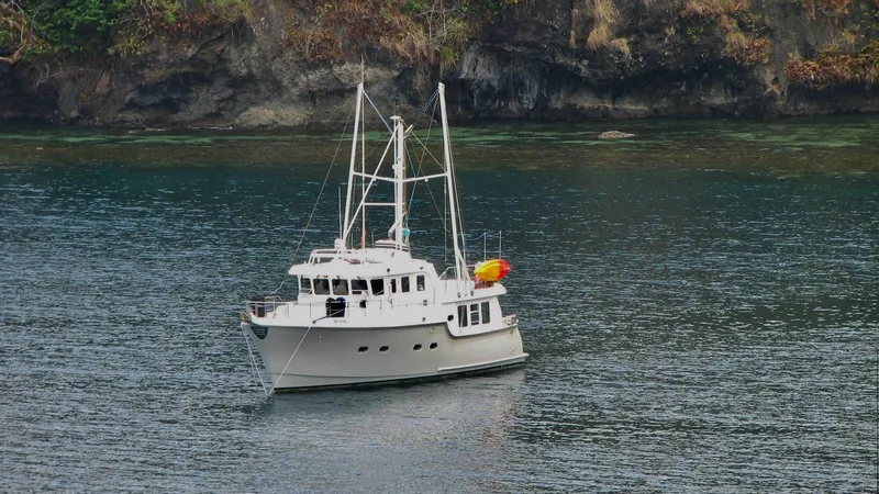 Bunyip I Yacht Photos Pics Nordhavn 47 yacht from 2002 anchored near rocky shoreline.