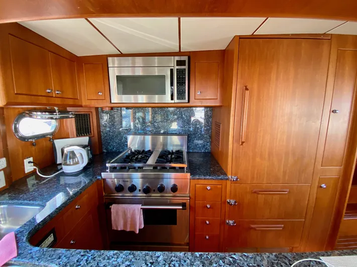 Bunyip I Yacht Photos Pics Luxurious kitchen in 2002 Nordhavn 47 yacht with wood cabinetry and modern appliances.