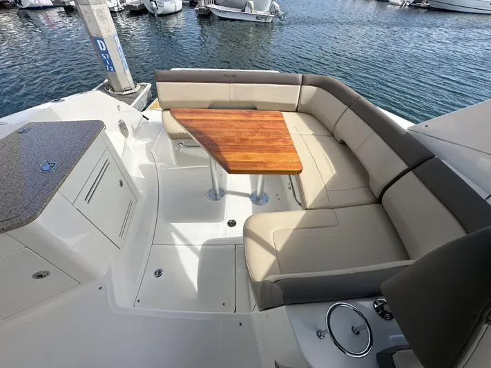 That's Amore Yacht Photos Pics 2015 Sea Ray 350 Sundancer boat interior with seating and wooden table by the water.