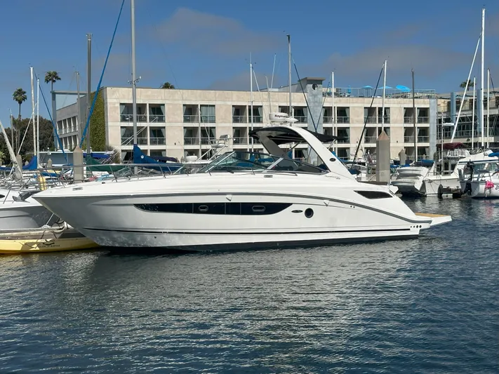That's Amore Yacht Photos Pics 2015 Sea Ray 350 Sundancer yacht docked in a marina, with modern buildings in the background.