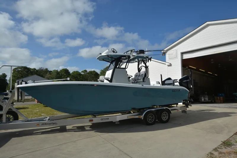 Carolina Bluewater Yacht Photos Pics 2024 Costa Custom Boats 264HC on trailer outside a garage under a blue sky.