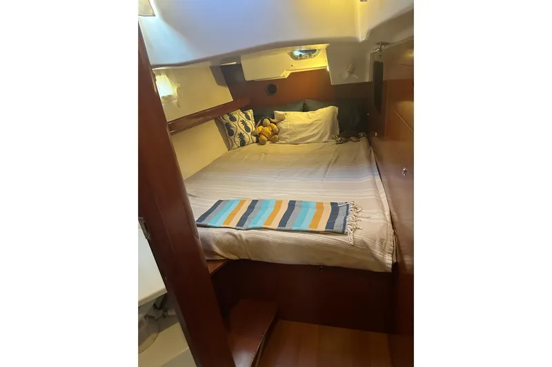  Yacht Photos Pics Cozy cabin interior of 2006 Beneteau Oceanis 523 sailboat with bed and colorful blanket.