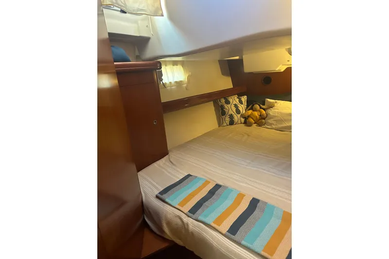  Yacht Photos Pics Cozy cabin interior of 2006 Beneteau Oceanis 523 sailboat with bed and decorative pillows.