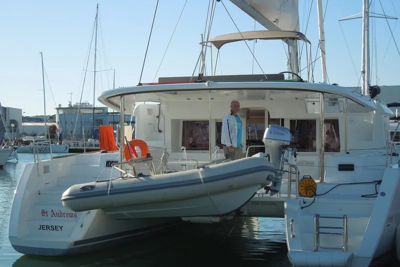 St Andrews Yacht Photos Pics 2014 Lagoon 450 F Owners Version catamaran docked with dinghy and person on deck.