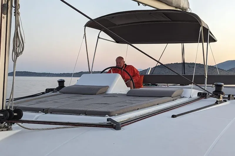 St Andrews Yacht Photos Pics Man steering 2014 Lagoon 450 F Owners Version catamaran at sunset.
