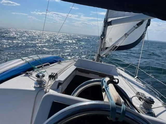 Sailing on a 2004 Hunter 306 yacht with clear skies and sparkling ocean.