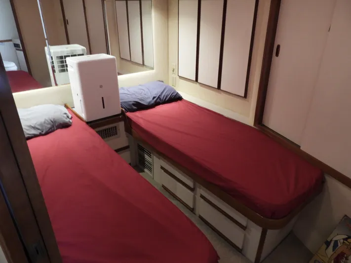  Yacht Photos Pics 1989 Bertram Convertible cabin with twin beds, red bedding, and mirrored walls.