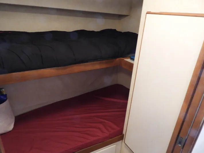  Yacht Photos Pics 1989 Bertram Convertible cabin with bunk beds, featuring black and red bedding.