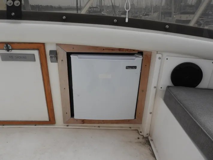  Yacht Photos Pics 1989 Bertram Convertible boat interior with mini fridge and seating area.