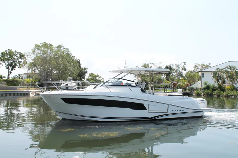 Over Exposed Yacht Photos Pics 2021 Jeanneau Leader 10.5 boat cruising on a calm waterway, surrounded by greenery.