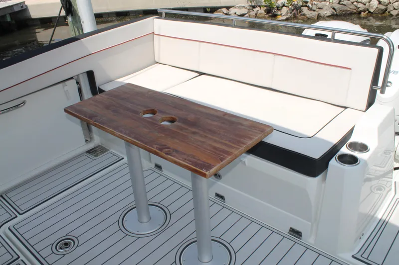Over Exposed Yacht Photos Pics 2021 Jeanneau Leader 10.5 boat deck with cushioned seating and wooden table.