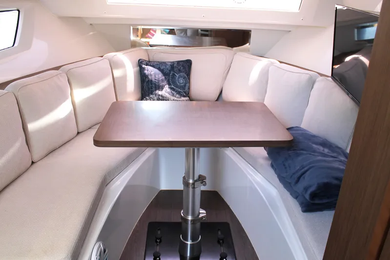 Over Exposed Yacht Photos Pics Cozy interior of 2021 Jeanneau Leader 10.5 with cushioned seating and table.