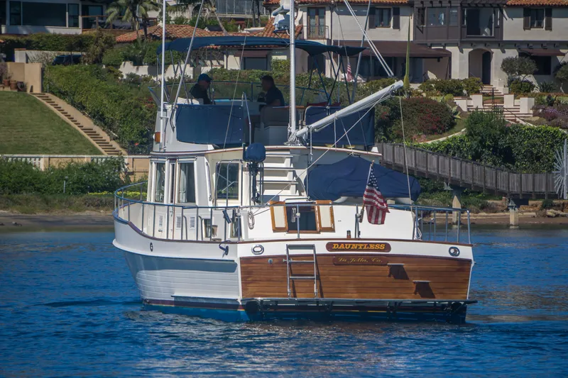 Dauntless Yacht Photos Pics 1995 Grand Banks 42 Classic yacht on water, with American flag, near waterfront homes.