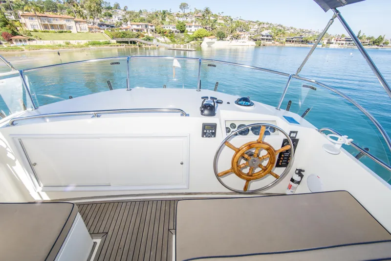 Dauntless Yacht Photos Pics Helm of 1995 Grand Banks 42 Classic yacht with wooden steering wheel and scenic waterfront view.