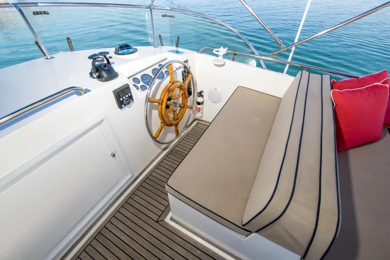 Dauntless Yacht Photos Pics Helm of 1995 Grand Banks 42 Classic yacht with wooden wheel and cushioned seating.