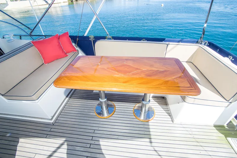 Dauntless Yacht Photos Pics Luxury seating area on 1995 Grand Banks 42 Classic yacht with wooden table and red cushion.
