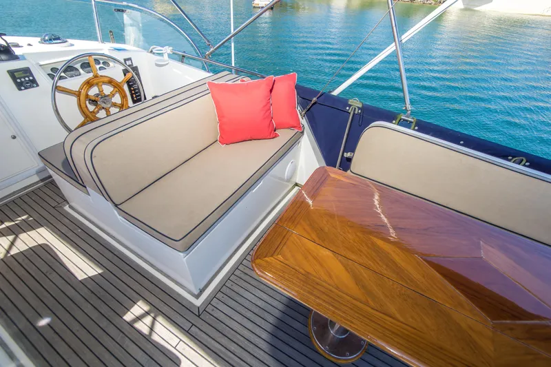 Dauntless Yacht Photos Pics Luxury seating area on 1995 Grand Banks 42 Classic yacht with wooden table and red cushion.