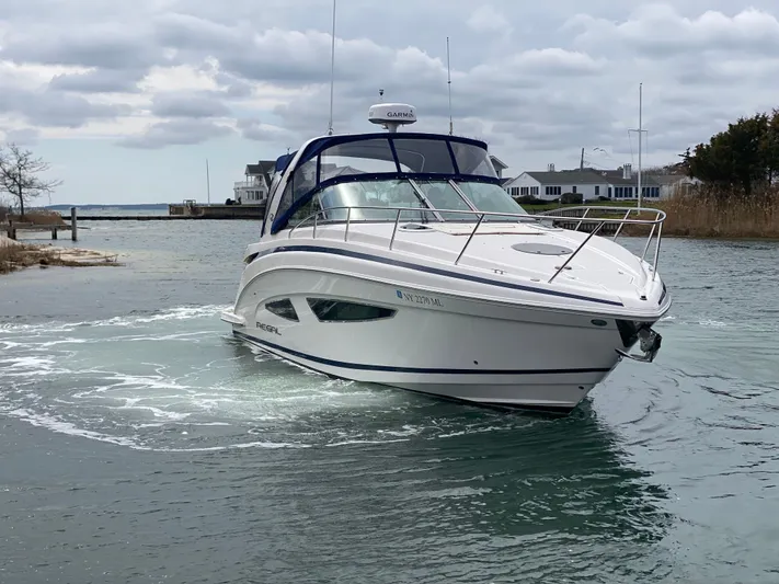  Yacht Photos Pics 2015 Regal 32 Express boat navigating a calm waterway under cloudy skies.